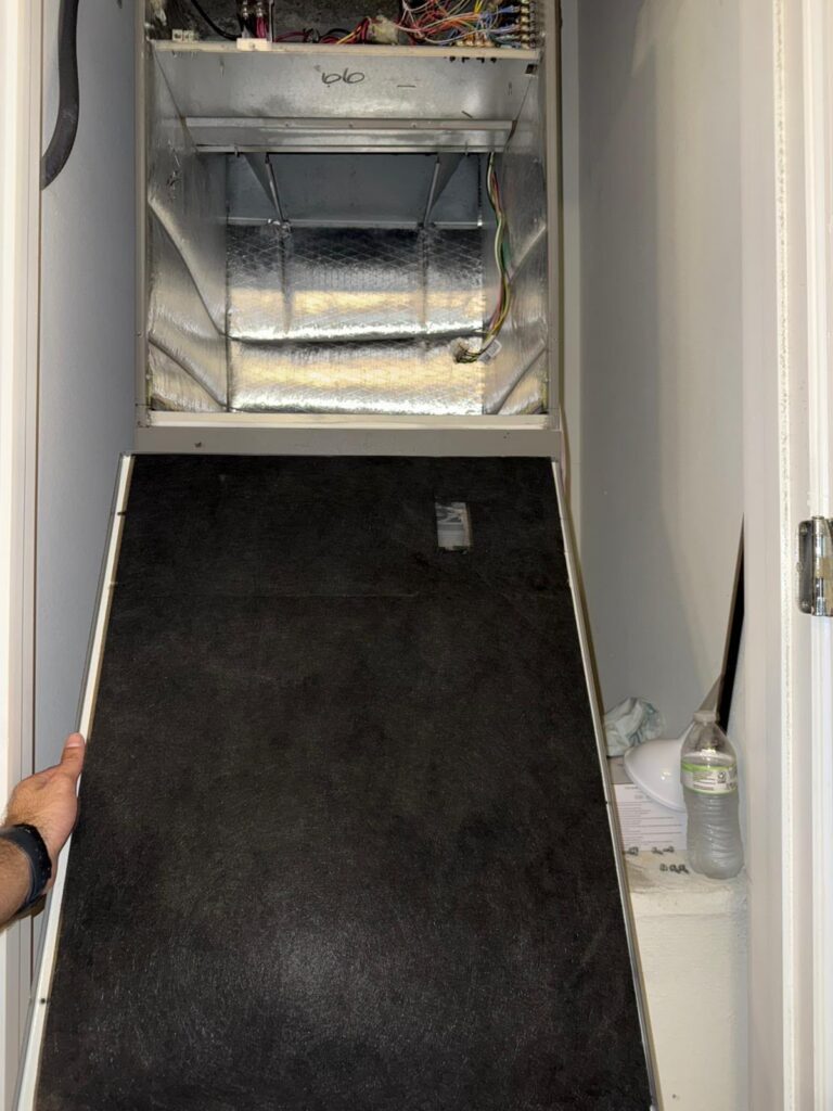 Technician holding a perfectly clean air filter in front of an A/C handler in Wesley Chapel FL